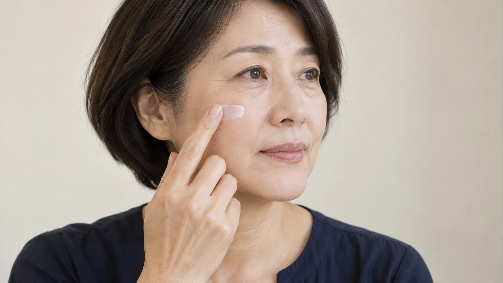 한 손 검지로 볼의 소량 흰 도포제를 가볍게 펴 바르는 중년 여성